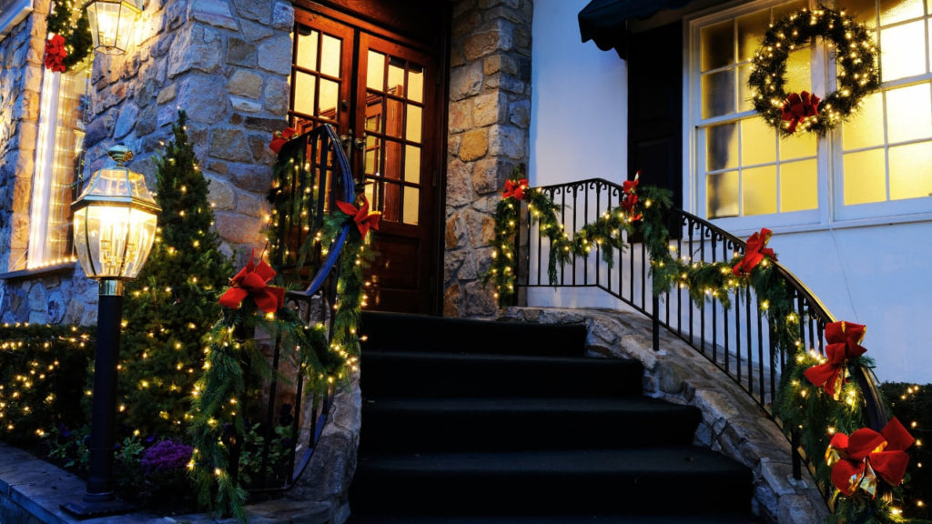 Imagem de casa americana decorada para o Natal com luzes coloridas e guirlanda na janela.