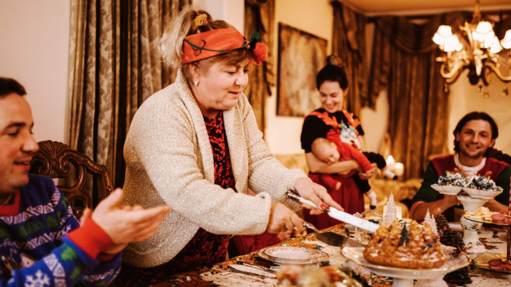 Família reunida ao redor da mesa para a ceia de Natal, com pratos tradicionais como peru assado e rabanada, simbolizando união e celebração.