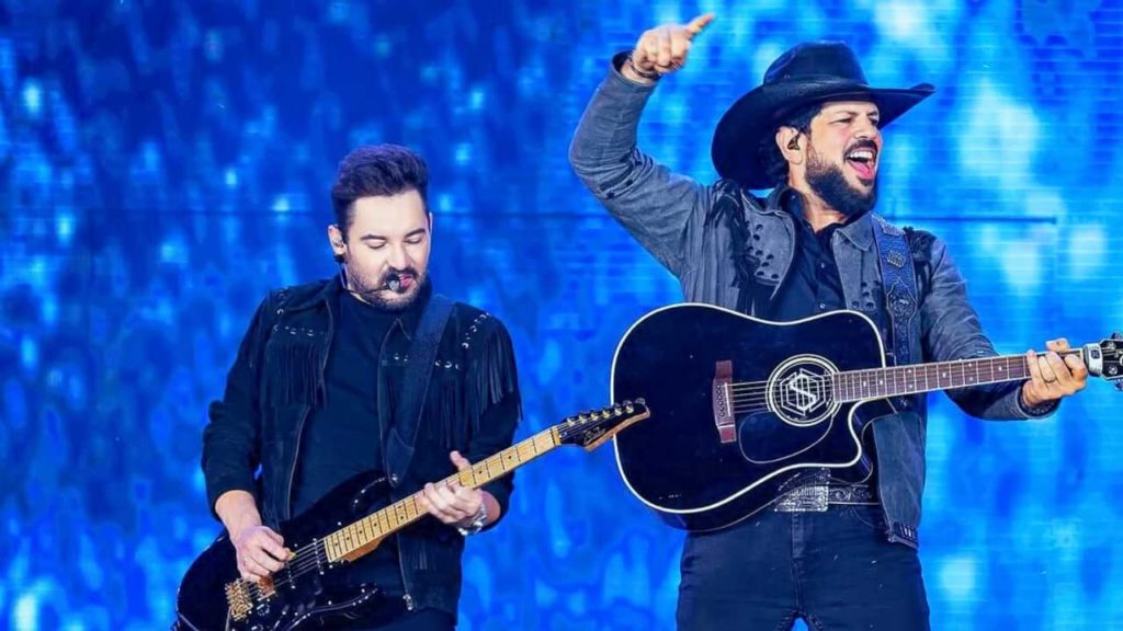 Fernando e Sorocaba cantando em um show de sertanejo, mostrando a energia e interação da dupla com o público.